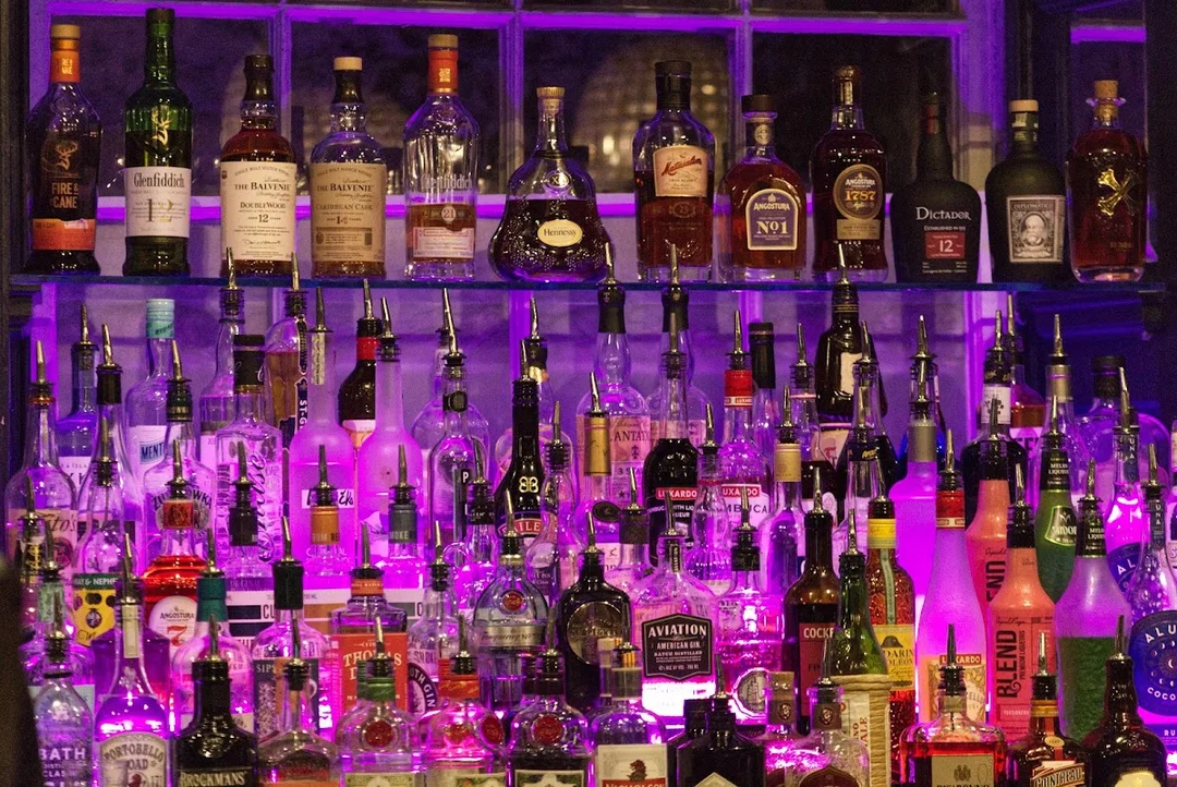 The dimly lit, vintage-style interior of The Bootlegger speakeasy bar in Bath, with cocktails on the bar.