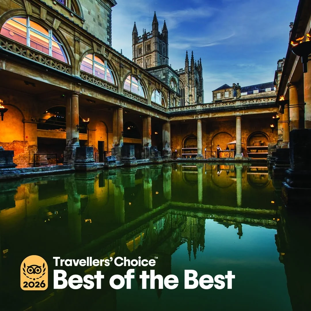 The Great Bath at the historic Roman Baths, with steam rising from the green thermal water surrounded by stone