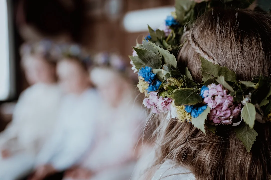 Back of a head with a flower crown of blue and purple blooms, others in background, at a Bath workshop